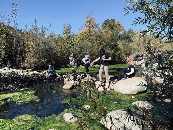 people standing on rocks in a creek pointing and looking down at the water