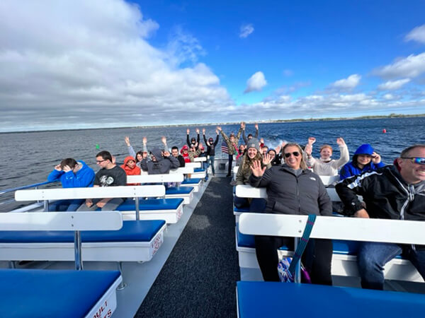 a group of people on a boat waving at the camera